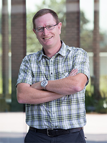 A headshot of Dr. Besançon wearing a plaid shirt.