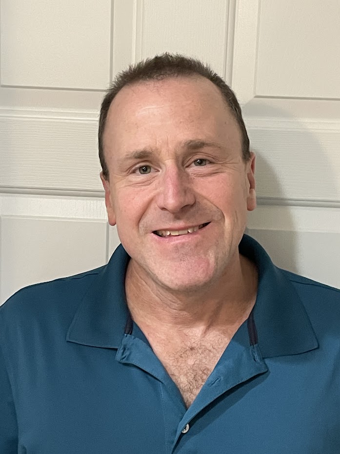 A headshot of Daniel Goldman wearing a blue shirt in front of a white background.