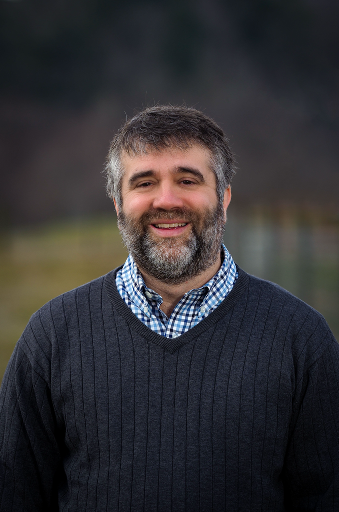 A headshot of Dr. Chris Reburg-Horton wearing a blue sweater and standing in a field.